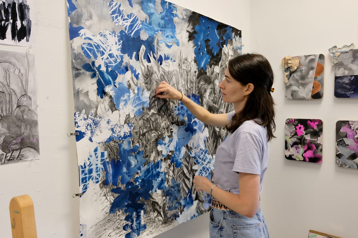 MFA student in studio with paintings.