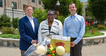 Alumni Neil Kerwin, Bronté Burleigh-Jones, and Michael Scher pose with fresh produce—offerings of the Airlie CSA program.