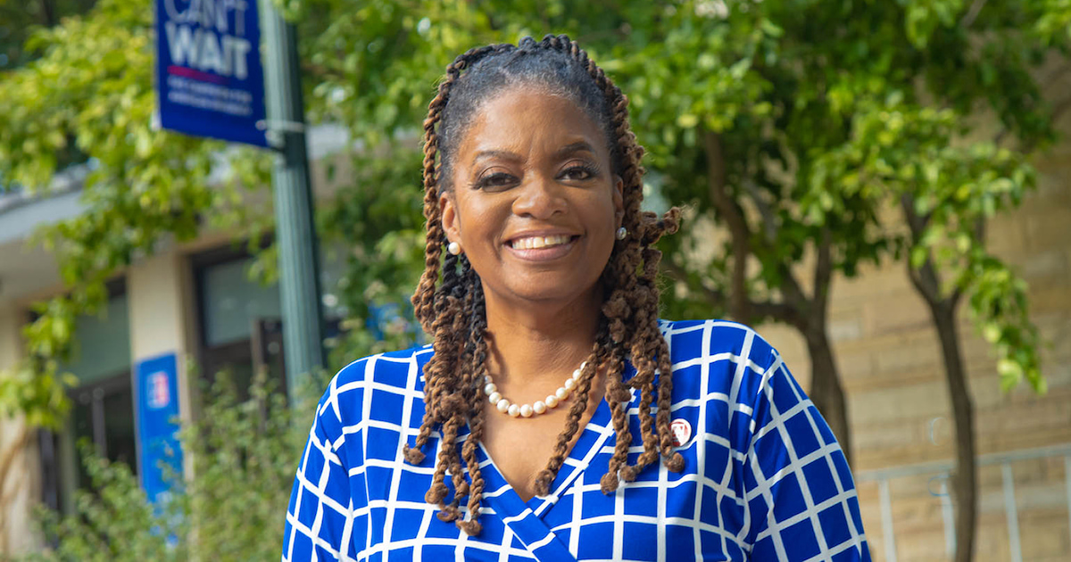 LaTanya Sothern, American University's new Alumni Association President, poses on campus. She smiles and wears blue and white—two of the university's colors.