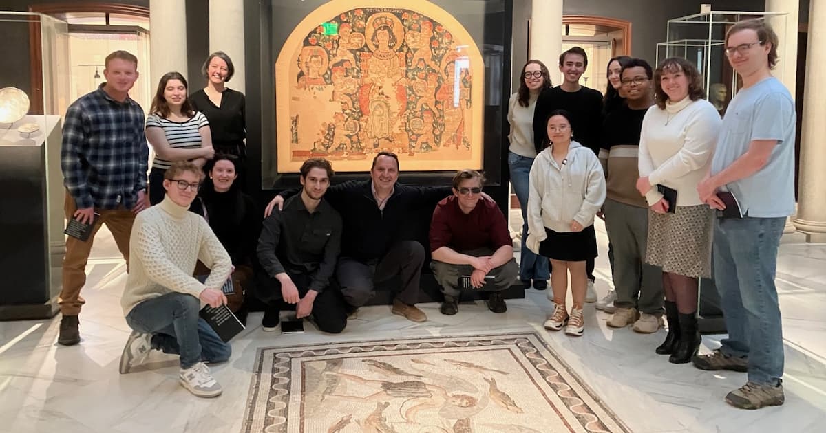 Student tour group in front of a Byzantine-era tapestry and floor mosaic.