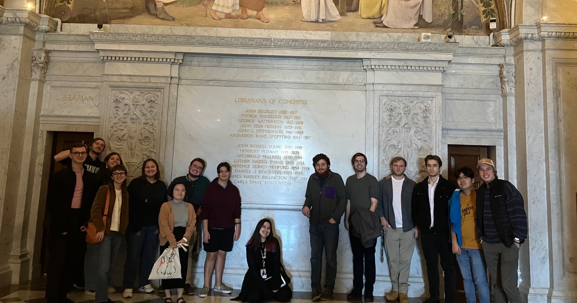 The students next to a gorgeously-decorated wall inside the Library of Congress.