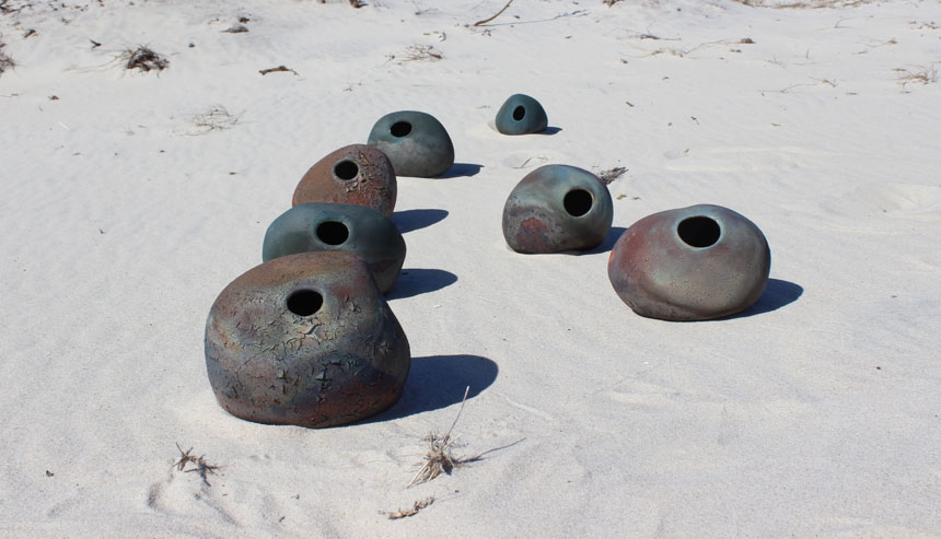 Sculptural arrangement of rocks-like vessels on sand