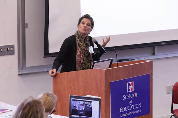 A woman speaks at a podium in front of the School of Education