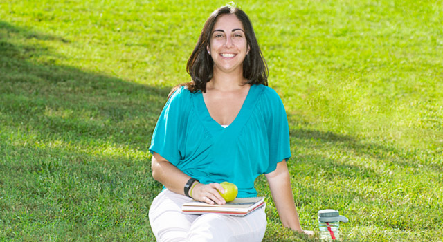 Person sitting on grass with books on lap