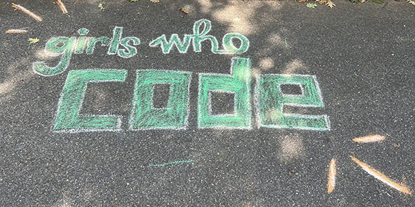 Girls Who Code logo drawn in chalk on asphalt