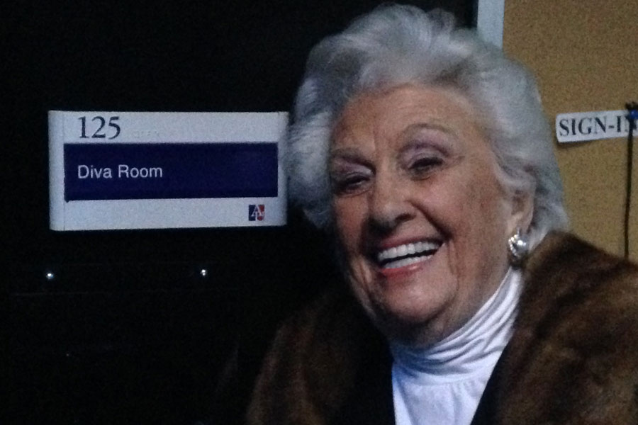 Sylvia Greenberg outside a door labelled 'Diva Room'