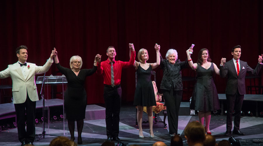 Sylvia Greenberg clasps hands in a line of performers on stage