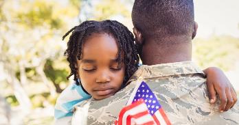 American soldier carrying child with flag.