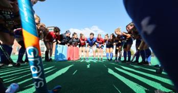 AU Field Hockey team gathered in a huddle with Coach Jennings.