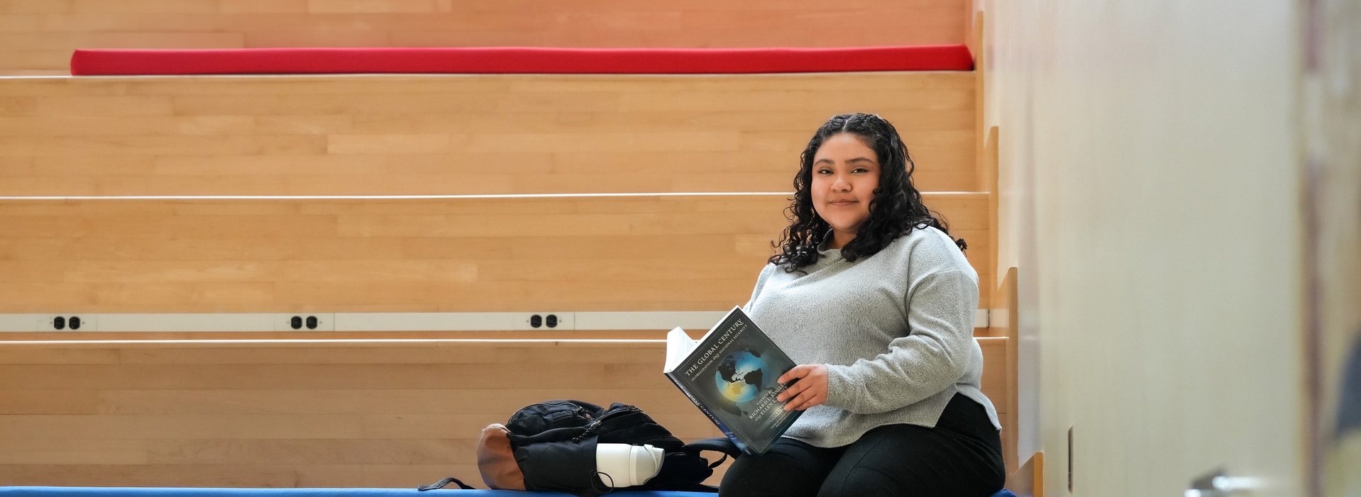 Rosy Chavez-Martinez sits reading on the steps in the School of International Service atrium at American University.