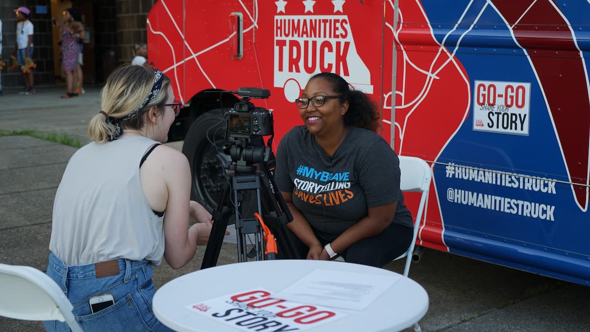 A woman is interviewed in front of the Humanities Truck