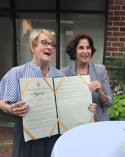 Linda Argo (left), holding the resolution presented to her from the D.C. government, by Mary Cheh (right)