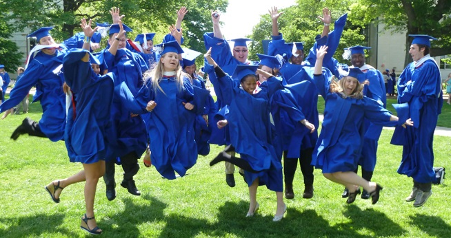 Students in graduation regalia, jumping