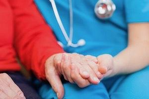 A nurse holds an elderly person's hand