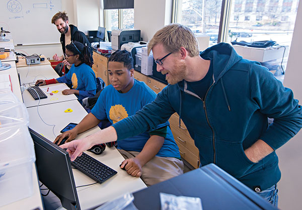 Students work at computer terminals with assistance from AU faculty