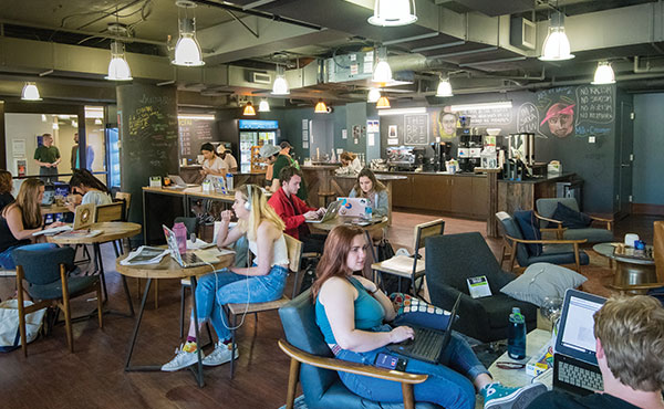 Students study on laptops at tables in the hip Bridge Cafe