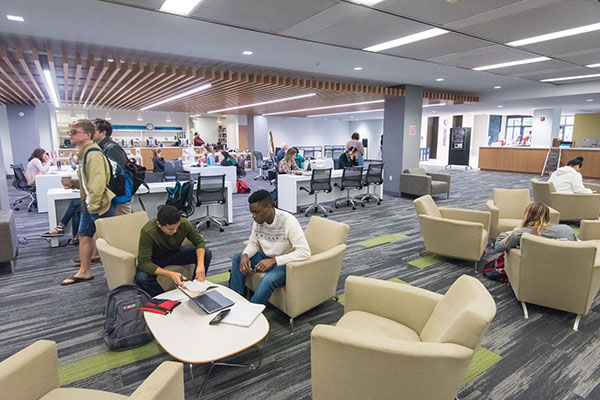 Students study in comfortable chairs in a light-filled library