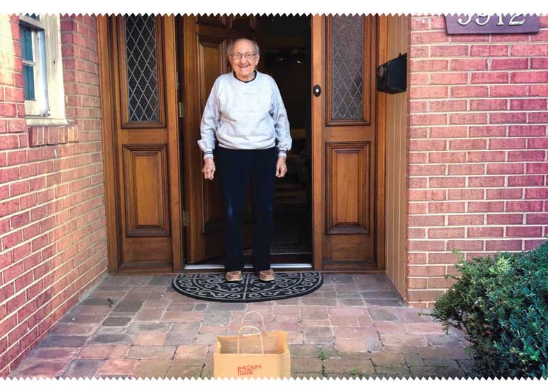 an elderly man stands in the doorway of his house
