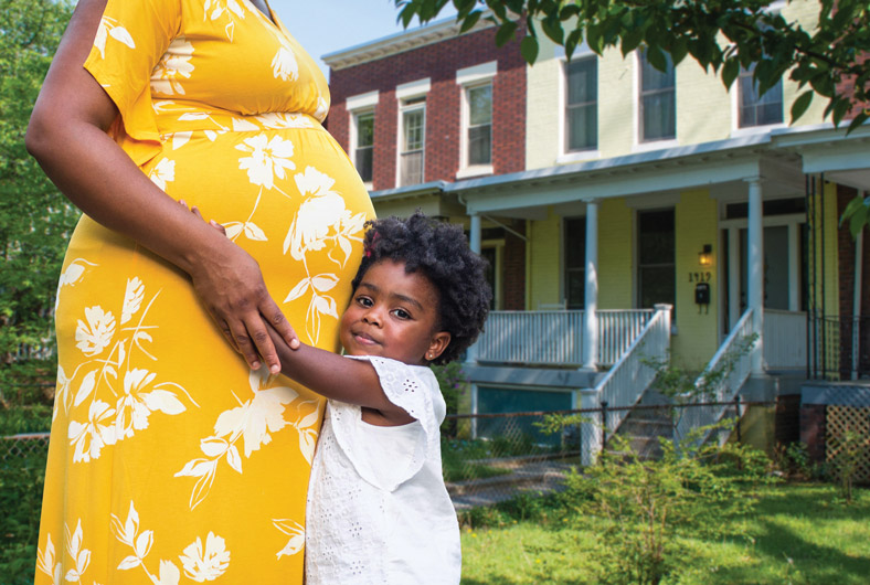 Pregnant Black woman hugging a small child