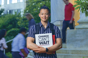 student holding a binder that reads "change can't wait"