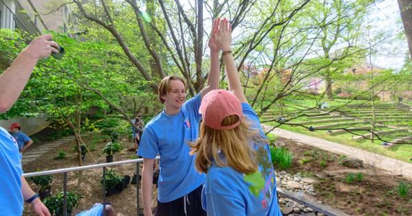 Two volunteers high five at Campus Beautification Day. Photo by Jeff Watts.