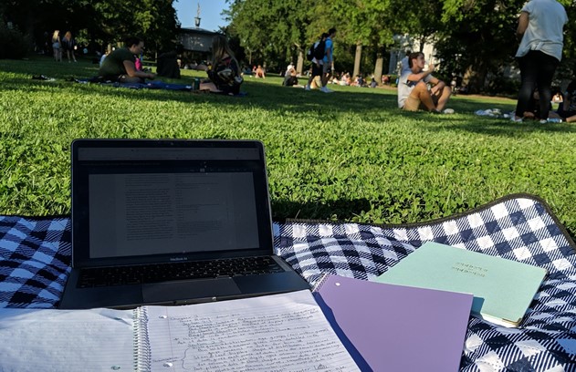 Photograph of a student studying on the quad.