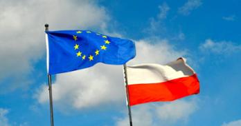 Polish and EU flags against a blue sky with some clouds