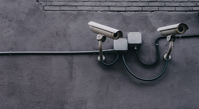 two security cameras attached to a brick wall