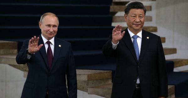 Russian President Vladimir Putin and People's Republic of China President Xi Jingping pose for a photo with waving hands