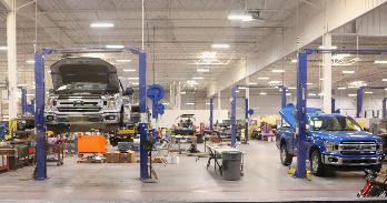 two Ford automobiles up on mechanical jacks in an automative manufacturing warehouse