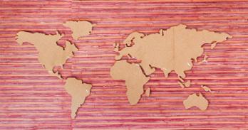 A cardboard world map is shown on top of a red textured background.