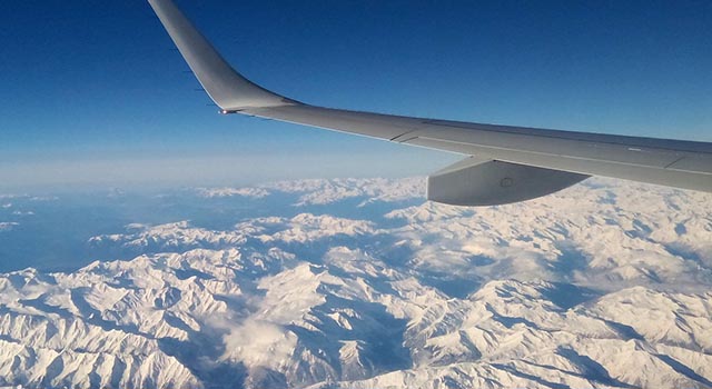 wing of airplane with snow covered mountains in view