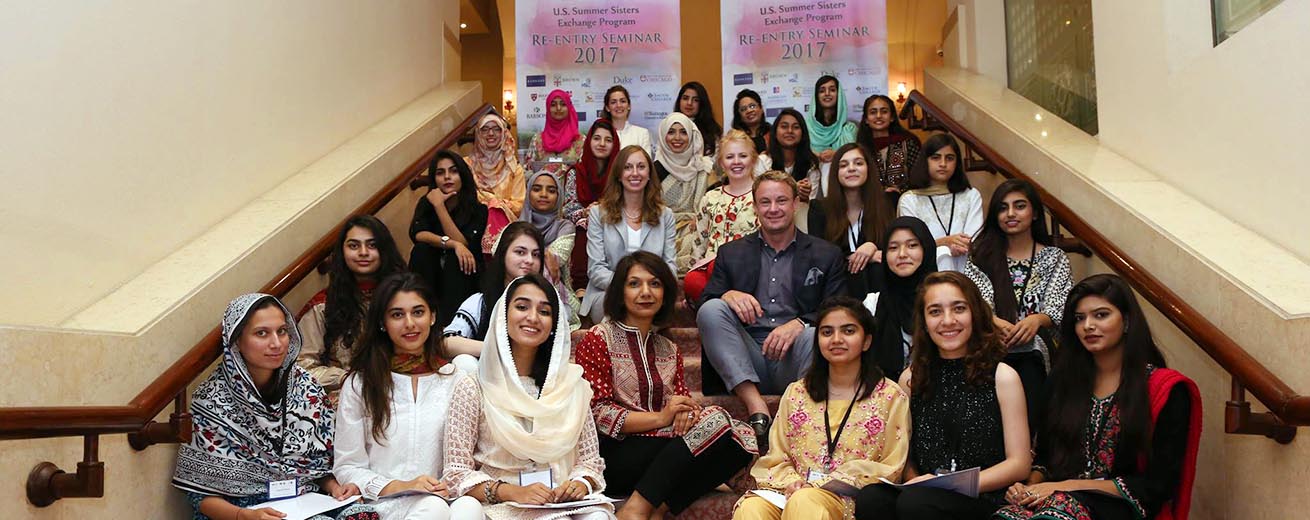 participants and staff from the Summer Sisters Exchange program from the US and Pakistan sit on the stairs