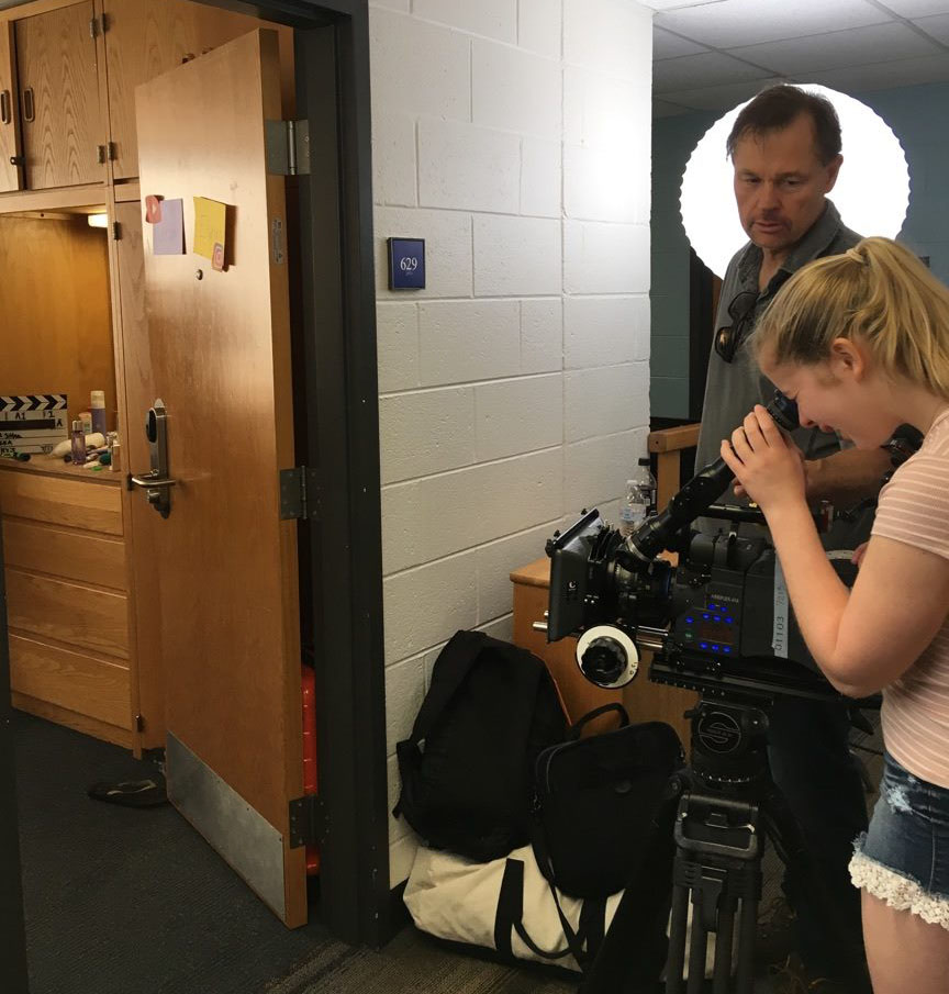 Students film the inside of a dorm room with a large movie camera