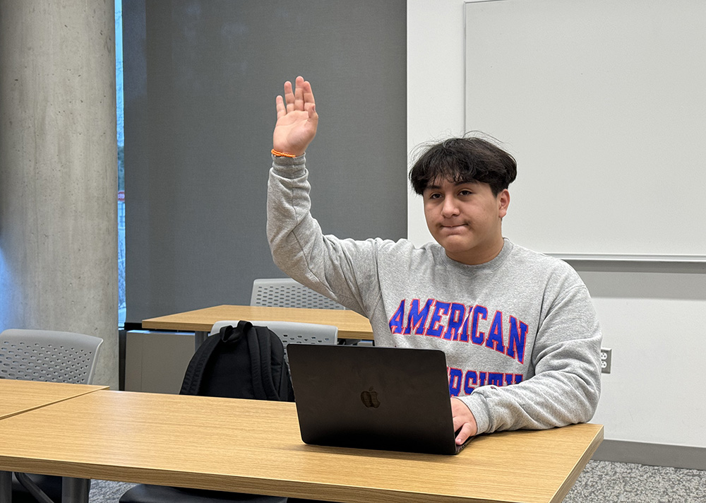 Luis Paredes raises his hand in a classroom.