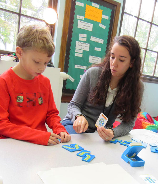 Young student playing a pattern-matching game with teacher.