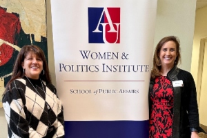 two women standing next to a wpi banner