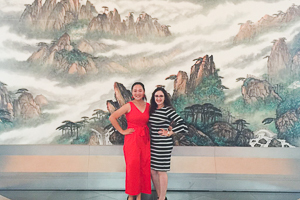 Jessica poses in front of a mural with fellow student at the Chinese Embassy