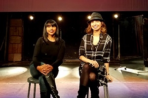 Leena Jayaswal and Caty Borum Chattoo sit on stools on a stage.