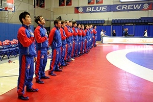The American University men's wrestling team stands with their hands over their hearts as the national anthem plays before a match in Bender Arena.