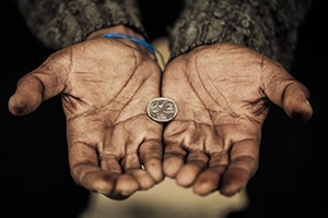Outstretched hands of a poor man with a quarter between the palms.