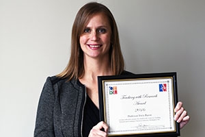 SPA Assistant Professor Tricia Bacon holds up her teaching with research award.