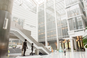 Wide view of the bright and high-ceilinged lobby of the World Bank headquarters. In the foreground is a bronze statue of a child and adult.