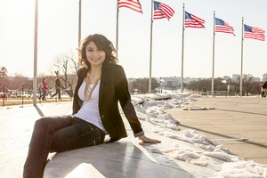 Meg Cusik poses in business attire with several flag poles in the background.