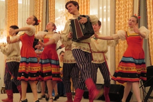 Young people in traditional costume dance and play the accordion onstage.