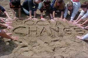Students writing social change in the sand.