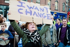 Woman holds up sign demanding change