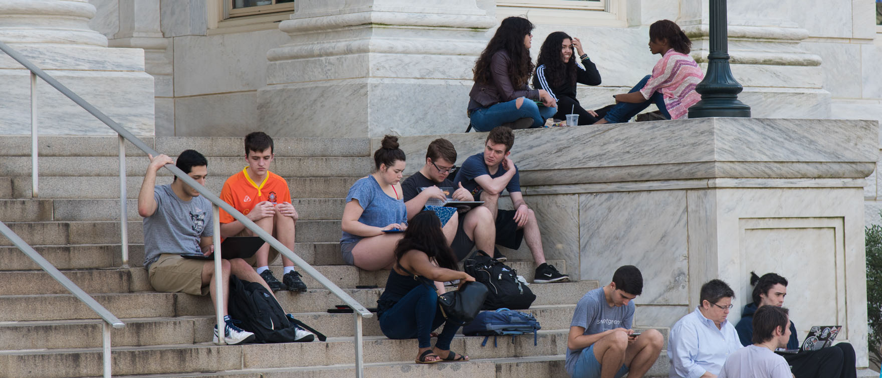 students sit on steps on campus quad