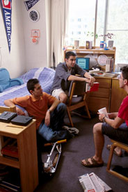 Three students hanging out in a dorm room.