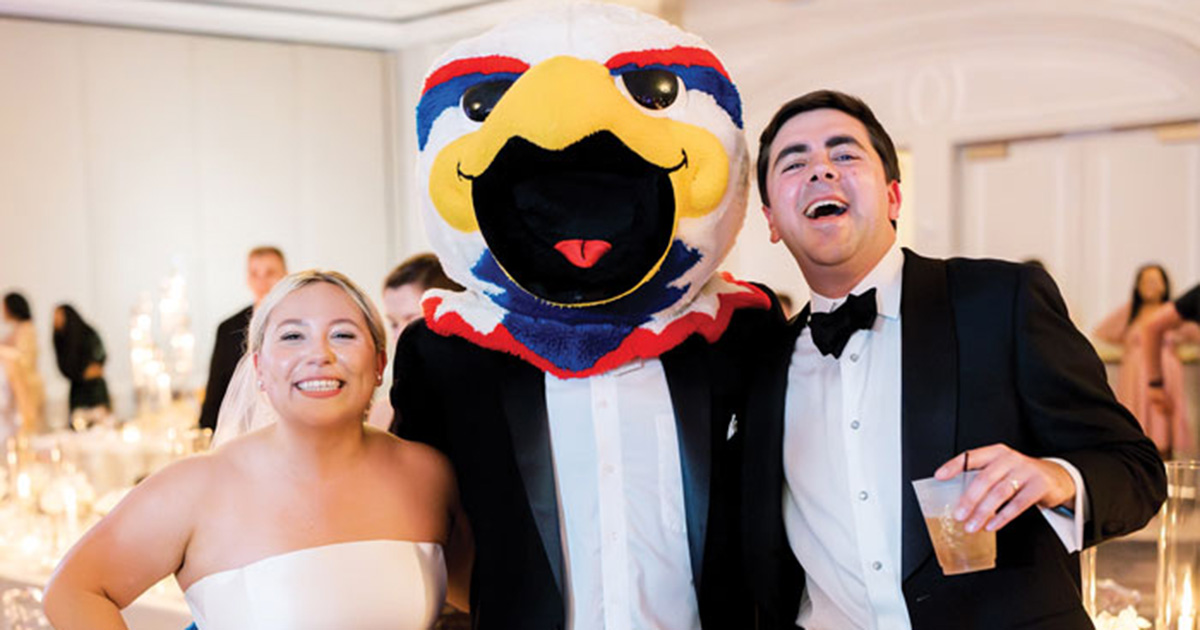 Two alumni pose with Clawed Z. Eagle at their wedding